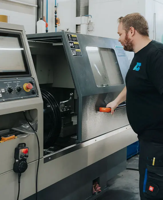 Mitarbeiter steht an einer Maschine zur Alufelgen Reparatur