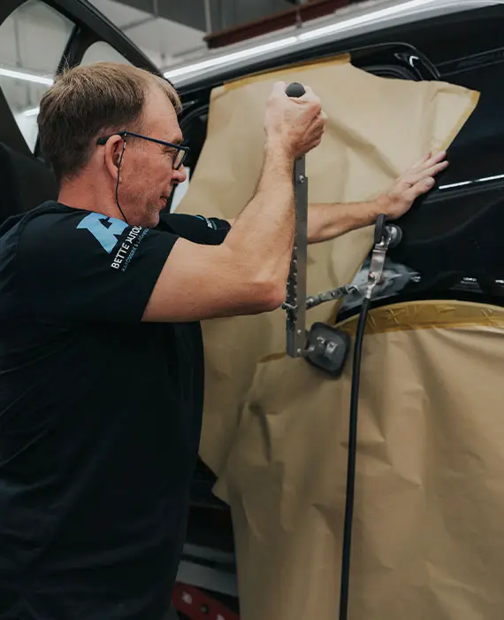 Mitarbeiter arbeitet an der Karosserie eines Autos