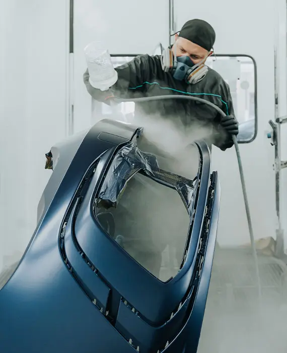 Mitarbeiter lackiert ein Karosserie Teil